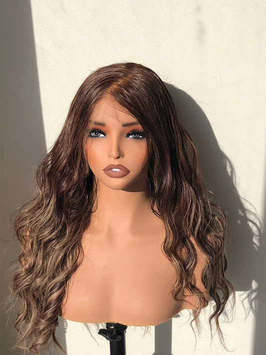 Mannequin head with long wavy brown wig on a neutral background